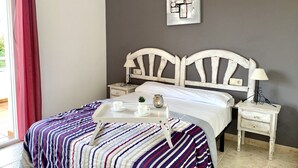 Ein Schlafzimmer mit einem Bett, Nachttischen, einer Lampe, einem Tablett mit Tassen und einem Einmachglas sowie einem Bild an der Wand.