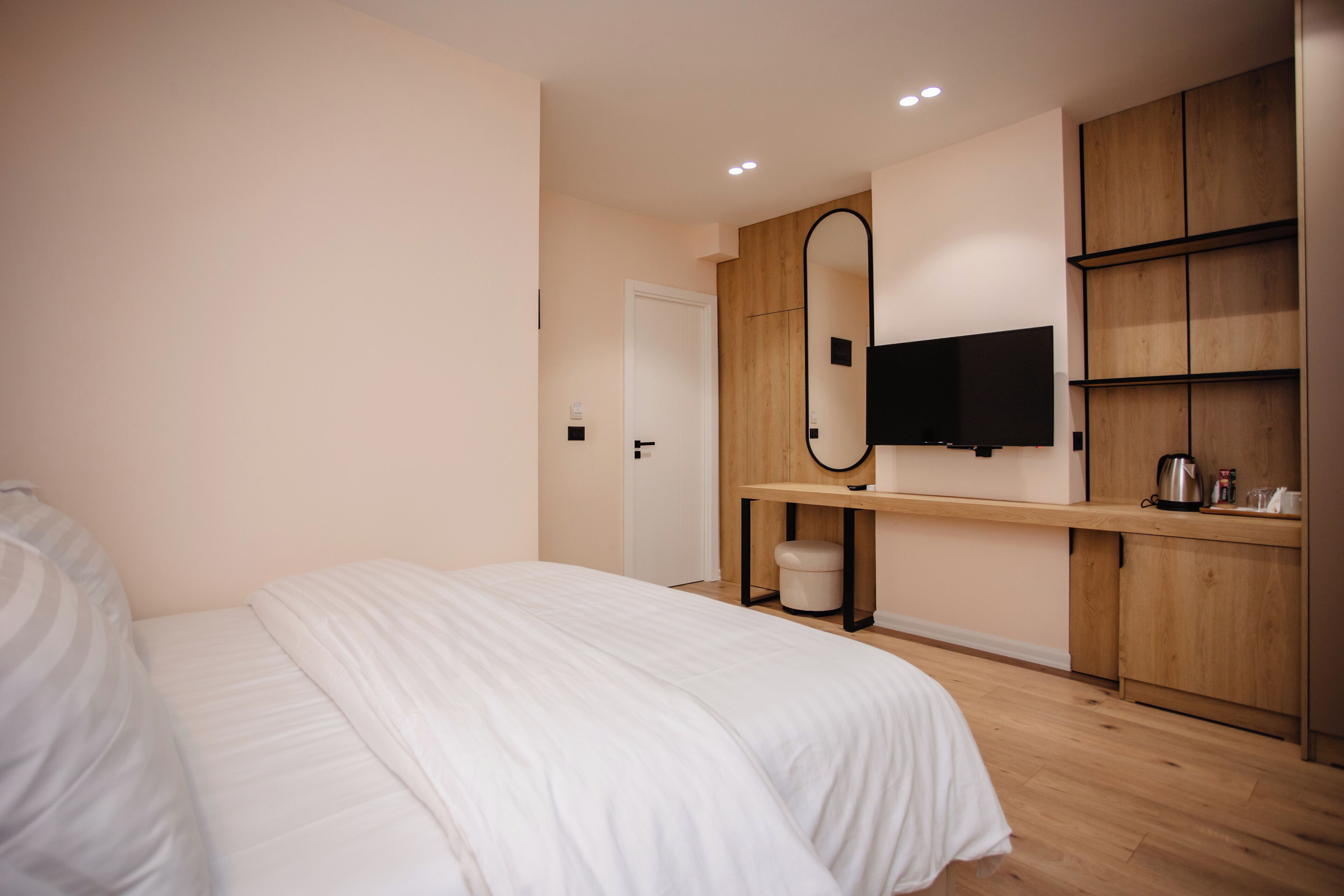 Un dormitorio con cama, un armario de madera, un espejo y un televisor en la pared.