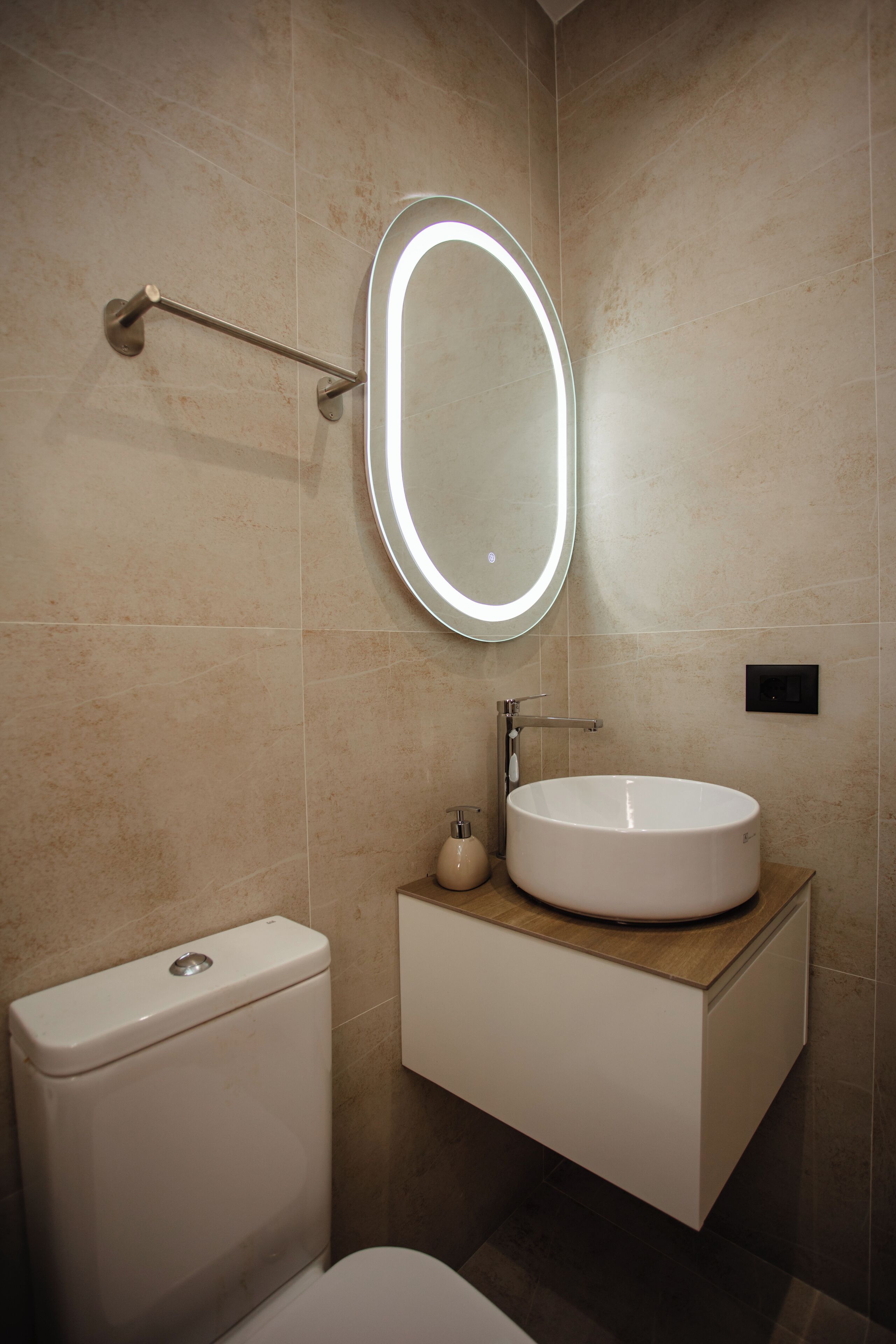 A modern bathroom with a round mirror, a white sink, and a toilet.
