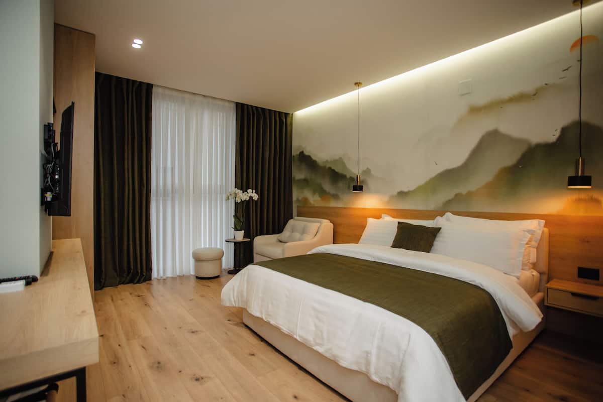 A modern bedroom with a large bed, a desk, and a wall-mounted TV.