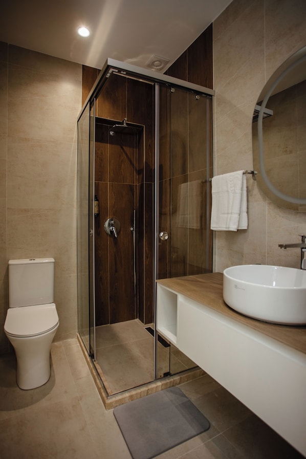 Un baño moderno con ducha envuelta en vidrio, un lavabo blanco y un inodoro.