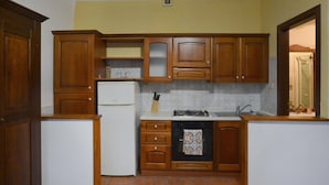 A compact kitchen with wooden cabinets, a white refrigerator, a stove, and a sink. - Gorgeous apartment in Arezzo with outdoor swimming pool (Arezzo)