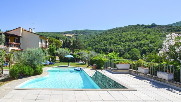 A swimming pool with a tiled deck, surrounded by greenery and a hillside. - Gorgeous apartment in Arezzo with outdoor swimming pool (Arezzo)