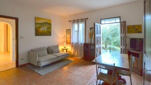 A living room with a sofa, a dining table with chairs, a TV, and a window with curtains. - Gorgeous apartment in Arezzo with outdoor swimming pool (Arezzo)