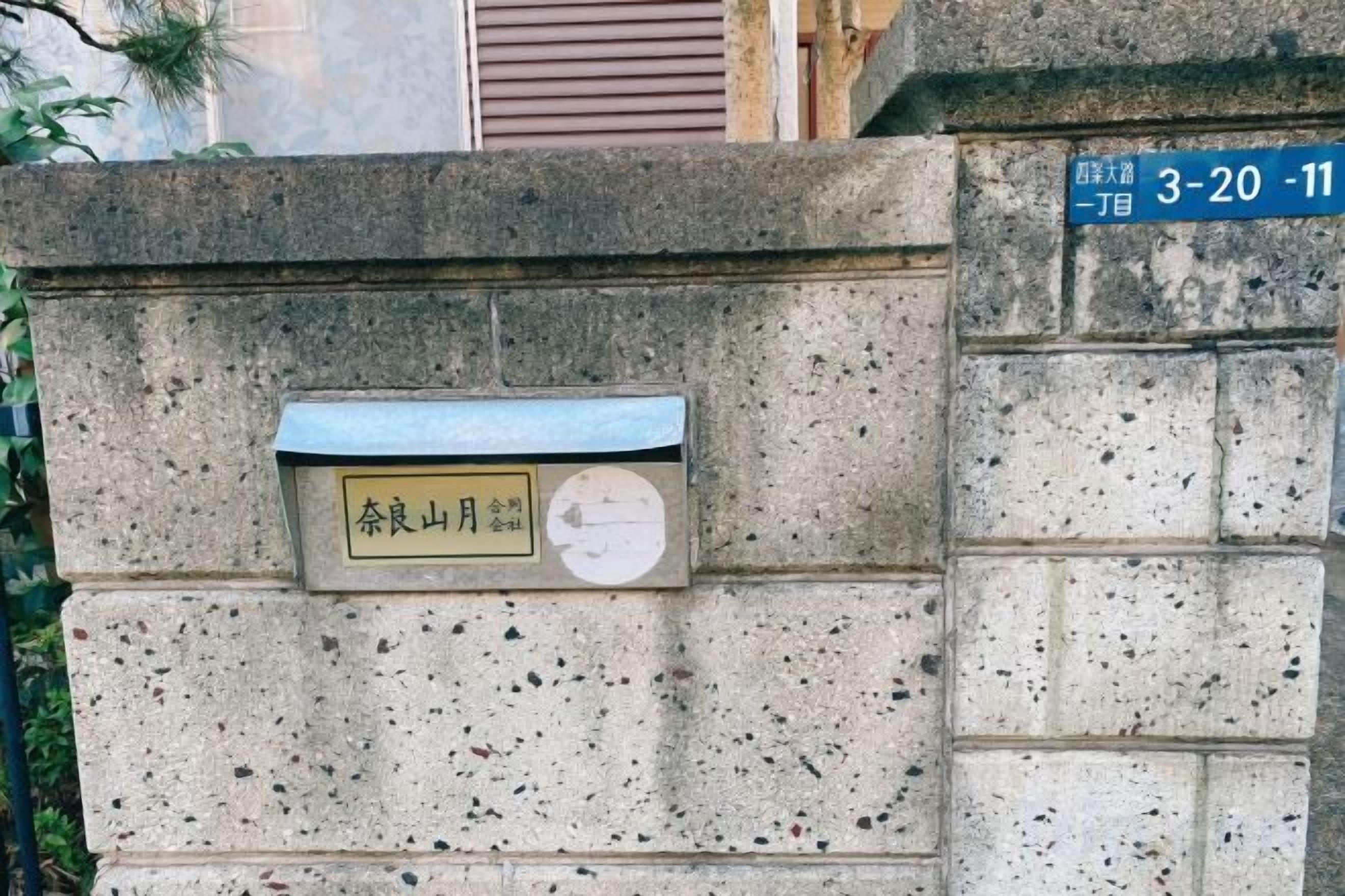 A stone wall with a mailbox and a street sign.