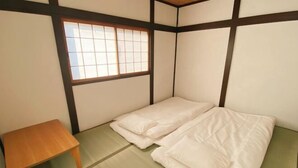 Une pièce de style japonais traditionnel, avec un sol recouvert de tatamis, une petite table en bois et un futon servant de lit.