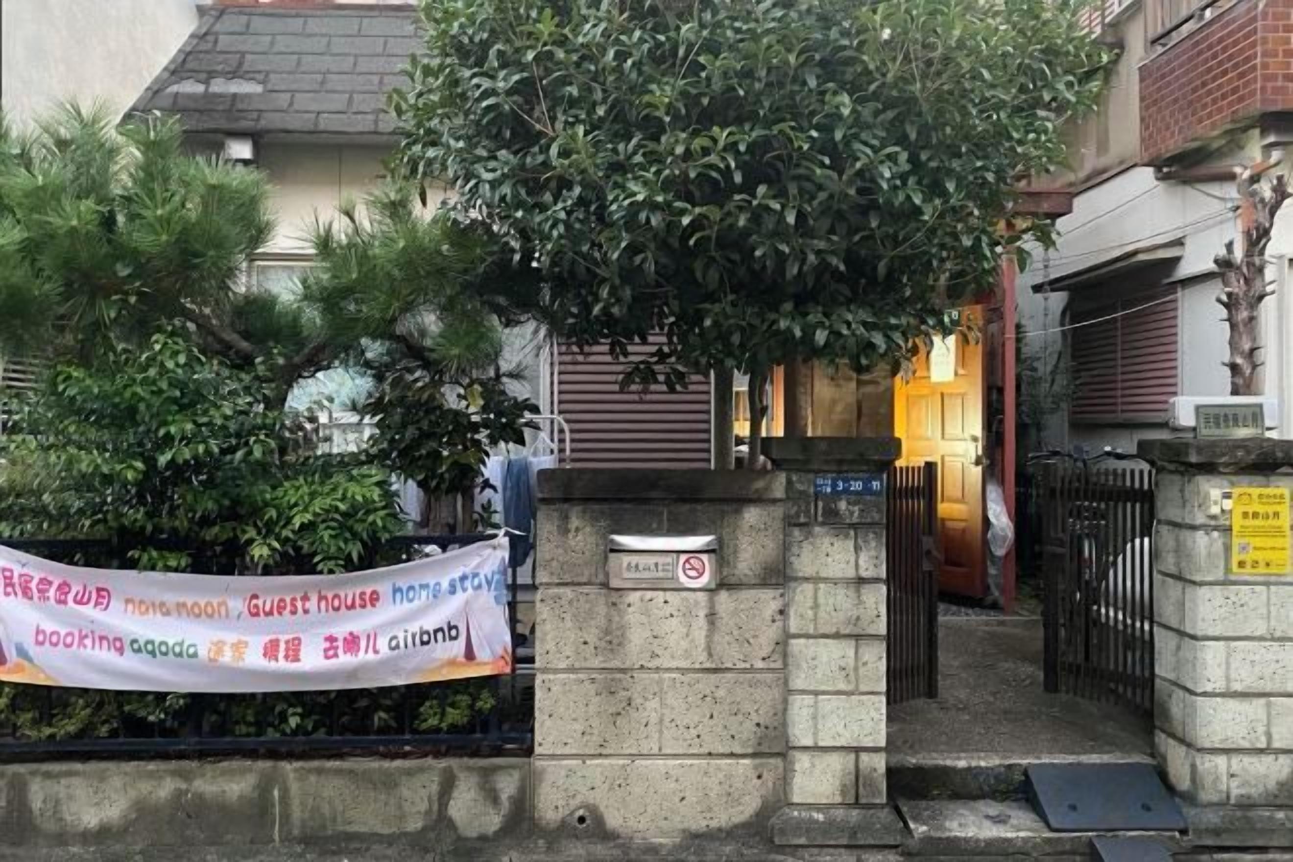 A gated entrance to a building with a banner advertising a guest house.