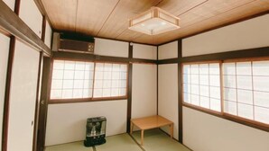 Une pièce de style japonais traditionnel, avec un sol recouvert de tatamis, des portes coulissantes et une petite table.