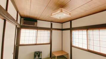 Una habitación japonesa tradicional con suelo de tatami, puertas correderas shoji, un calentador y techo de madera.