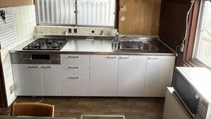 Une cuisine de taille réduite équipée d’une cuisinière à gaz, d’un évier et d’un four à micro-ondes.