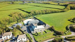 A large estate with multiple buildings, expansive green fields, and a winding road. - Attractive cottage two minute walk to the beach, dog friendly, parking (Harlyn)
