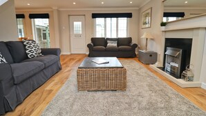 A living room with two sofas, a coffee table, a fireplace, and a door. - Attractive cottage two minute walk to the beach, dog friendly, parking (Harlyn)
