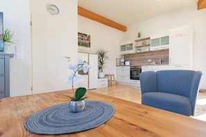 A modern kitchen with white cabinets, a wooden countertop, and a blue chair.