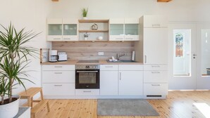 Een moderne keuken met witte kasten, een ingebouwde oven en een koffiezetapparaat.