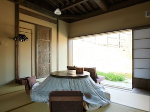 A tatami room with a round table, chairs, and a sliding door. - Kominka Neri (Miyawaka)
