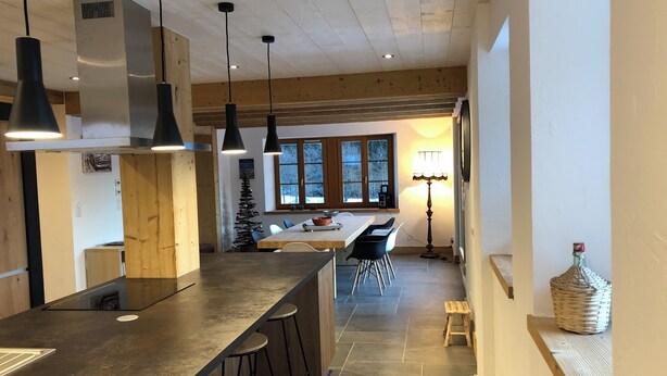 Una cocina moderna con una isla grande, taburetes de bar, luces colgantes y una isla central con estufa.