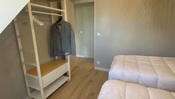 Une chambre avec un lit en mezzanine, un lit superposé, une armoire en bois et un luminaire suspendu.