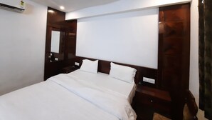A bedroom with a bed, a ceiling fan, a wall-mounted air conditioner, and a wooden headboard.