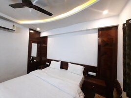 Un dormitorio con cama, ventilador de techo, aire acondicionado de pared y cabecero de madera.
