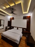 Un dormitorio moderno con una cama grande, cabecera de madera e iluminación empotrada en el techo.