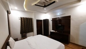 A hotel room with a bed, a TV, a wardrobe, and a ceiling fan.