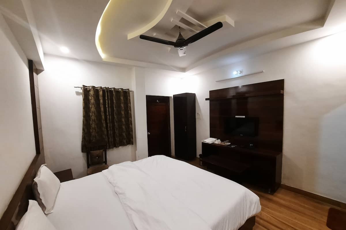 A hotel room with a bed, a TV, a wardrobe, and a ceiling fan.