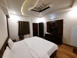 Habitación de hotel con cama, televisor, armario y ventilador de techo.