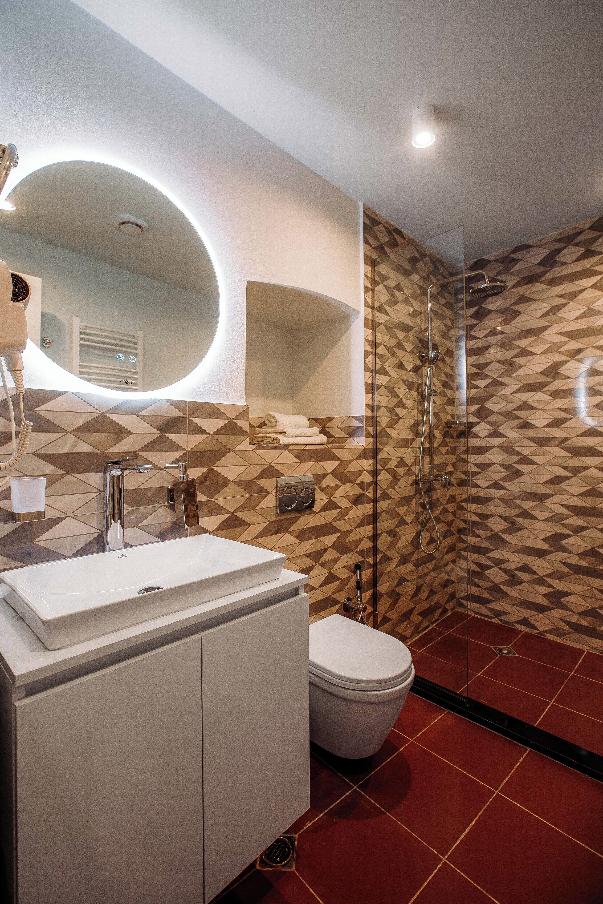 A modern bathroom with a white sink, a mirror, a toilet, and a shower.