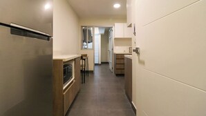 A narrow, modern kitchen with a stainless steel refrigerator, wooden cabinets, and a built-in oven. - w* | Premium 2BR with Balcony near the Malecon (Miraflores)