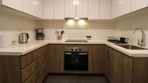 A modern kitchen with white cabinets, stainless steel appliances, and a black oven. - w* | Premium 2BR with Balcony near the Malecon (Miraflores)