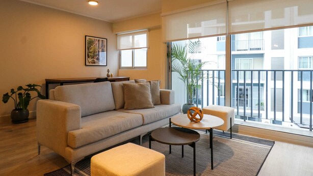 A modern living room with a sofa, a coffee table, and a potted plant. - w* | Premium 2BR with Balcony near the Malecon (Miraflores)