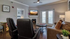 A living room with a fireplace, a television, and a ceiling fan. - Mountain View Condo by Beyond Expectations: 2BR w/ Pools, Balcony & King Beds (Pigeon Forge)