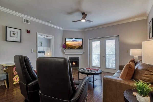 Una sala de estar con chimenea, televisor y ventilador de techo.