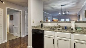 A modern kitchen with granite countertops, white cabinetry, and a black dishwasher. - Mountain View Condo by Beyond Expectations: 2BR w/ Pools, Balcony & King Beds (Pigeon Forge)