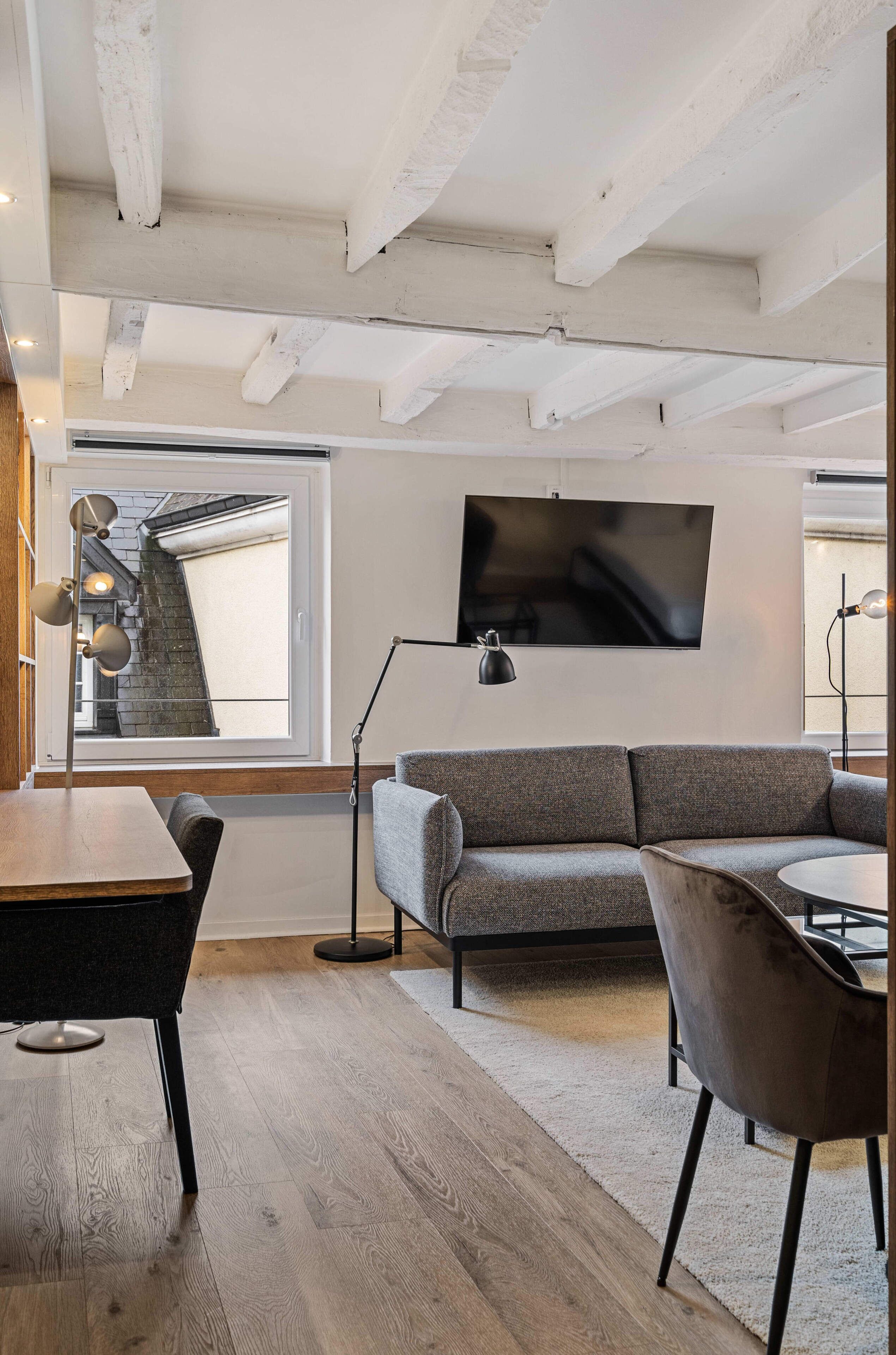 A modern living room with a grey sofa, a round coffee table, and a TV mounted on the wall.