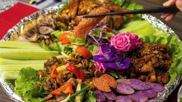 A meal with various dishes including meat, vegetables, and purple-colored items, served on a foil-covered tray.