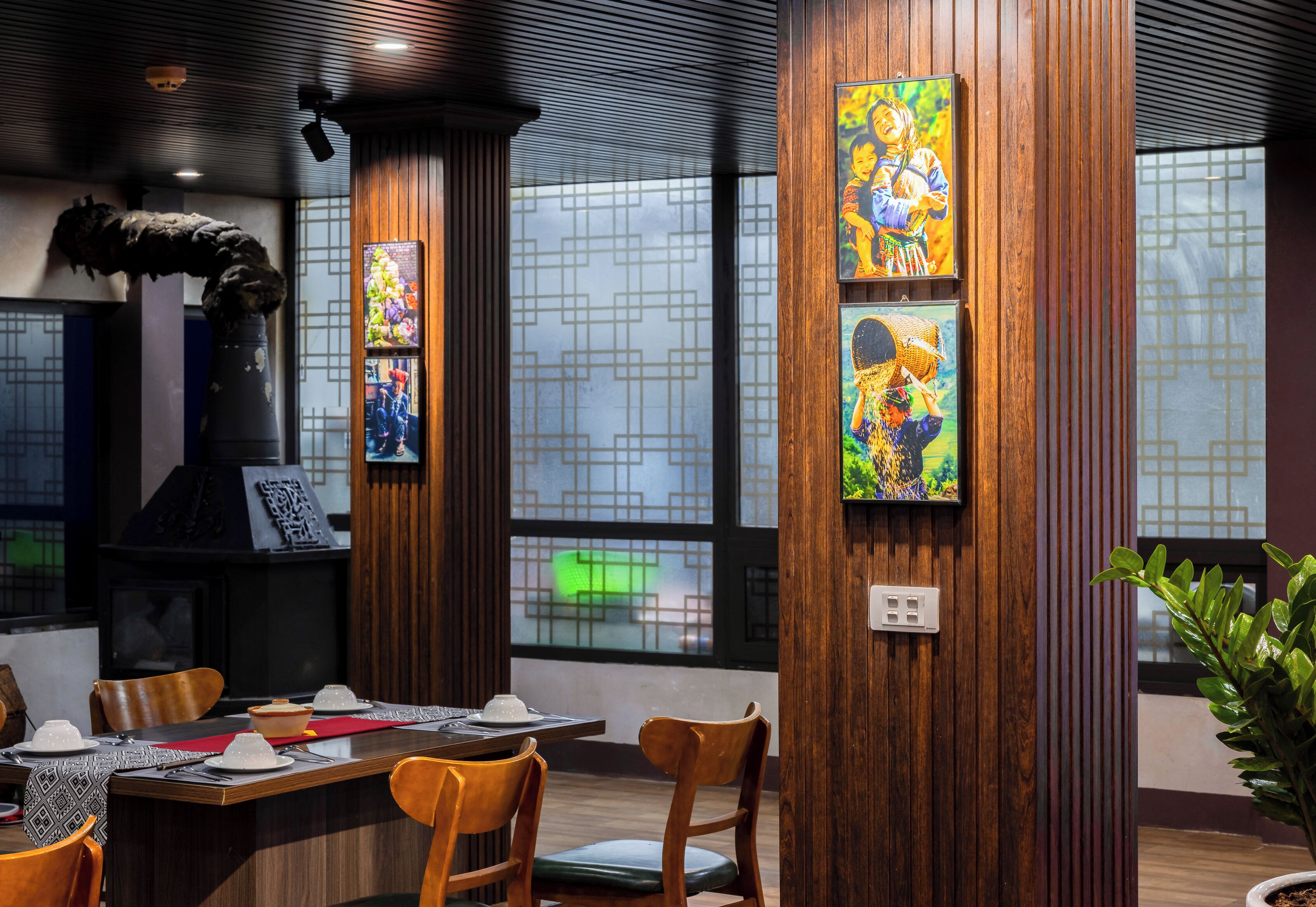 Interior de restaurante con paneles de madera, un ventanal con vistas y obras de arte en las paredes.