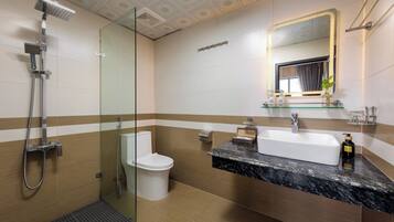 A modern bathroom with a glass shower enclosure, a white toilet, a marble sink, and a mirror with a lighted frame.