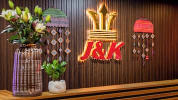 A reception desk with a wooden panel background, a vase with flowers, and decorative hanging ornaments.