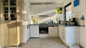 Eine kompakte Küche mit weißen Schränken, einem eingebauten Ofen und einem Essbereich mit kleinem Tisch und Stühlen.