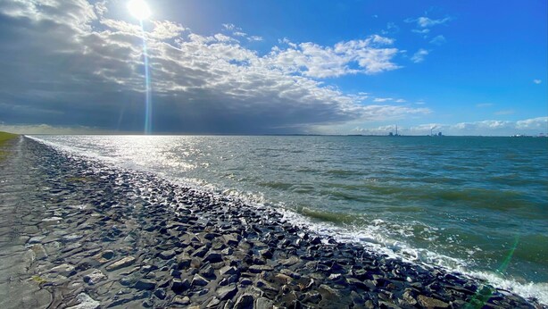 Eine felsige Küste, auf die Wellen unter einem klaren Himmel branden.