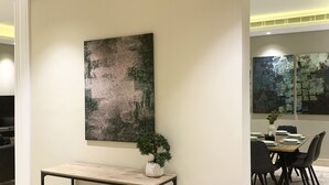 Ein moderner Essbereich mit einem Tisch für vier Personen, einem Blumentopf und einem großen abstrakten Gemälde an der Wand.