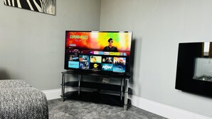 A flat-screen TV on a stand in a room with a carpeted floor and a framed picture on the wall. - 4 Bedrooms Full House Stourbridge Birmingham (Stourbridge)