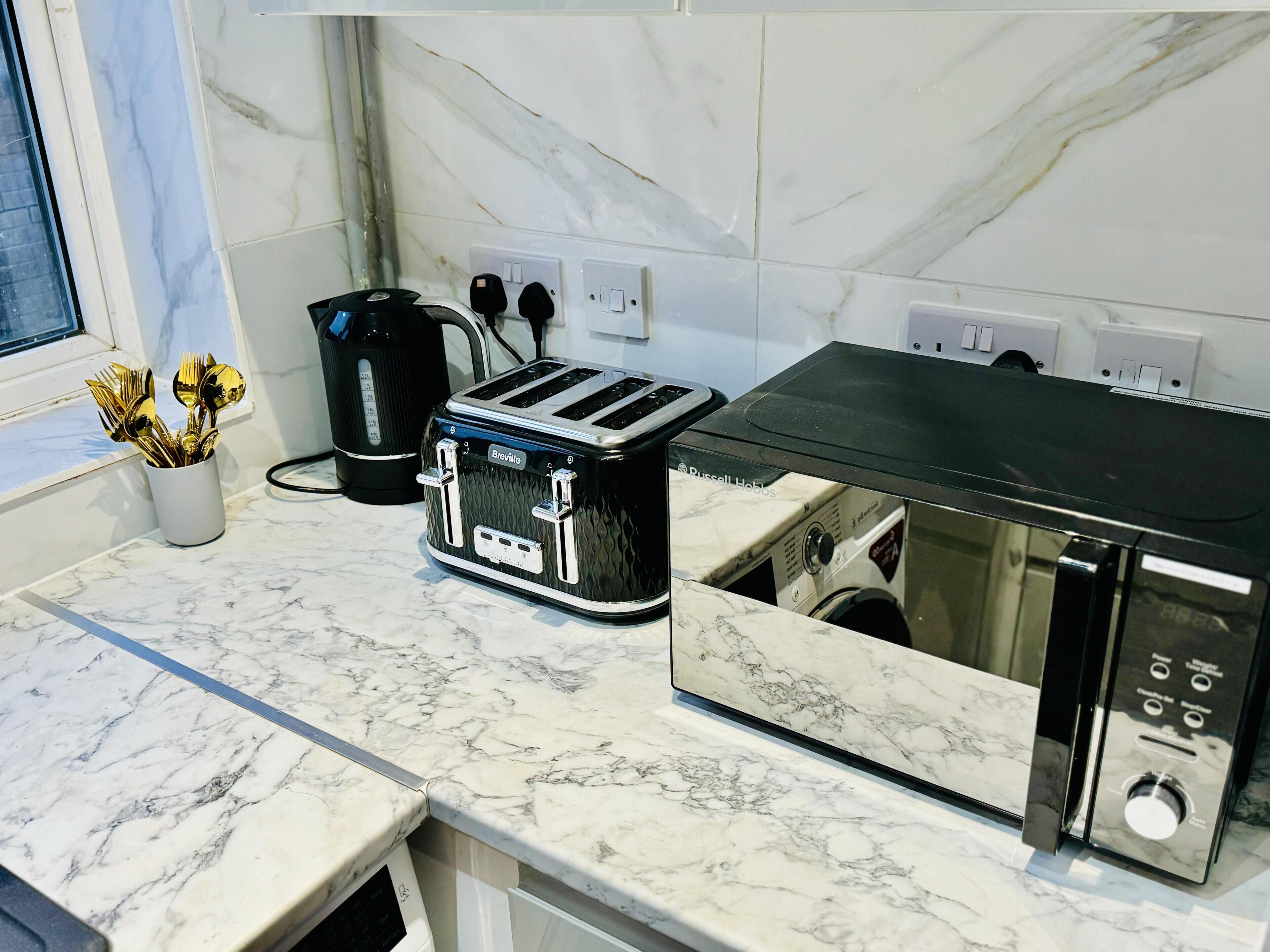 Une cuisine équipée d’un grille-pain Breville, d’une bouilloire et d’un plan de travail en marbre.