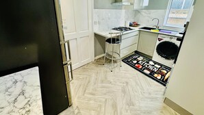 A compact kitchen with a white countertop, a stainless steel sink, a built-in oven, and a washing machine. - 4 Bedrooms Full House Stourbridge Birmingham (Stourbridge)