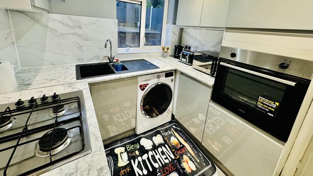 A compact kitchen with a sink, stove, oven, and a washing machine. - 4 Bedrooms Full House Stourbridge Birmingham (Stourbridge)