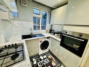 Cocina compacta con lavabo, estufa, horno y lavadora.