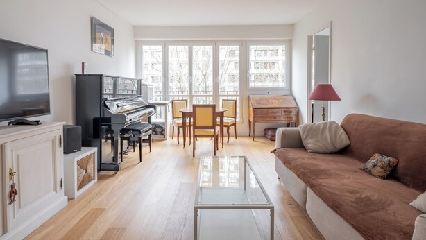 Un salón amplio con televisión, piano y sofá.