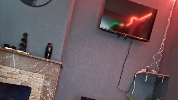 Una sala moderna con una mesa de centro de mármol, dos sofás, un televisor de pantalla plana montado en la pared y una planta pequeña.