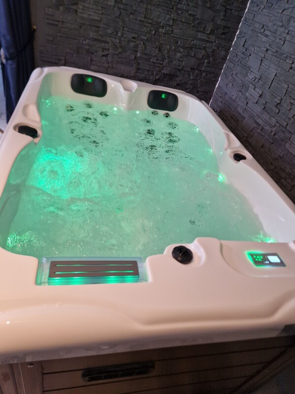 A spa bathtub with green lighting and a control panel.